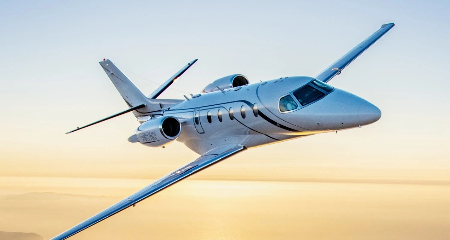 Cessna Citation Ascend in flight over the sea at sunset, a midsize jet available for charter through IBC Aviation