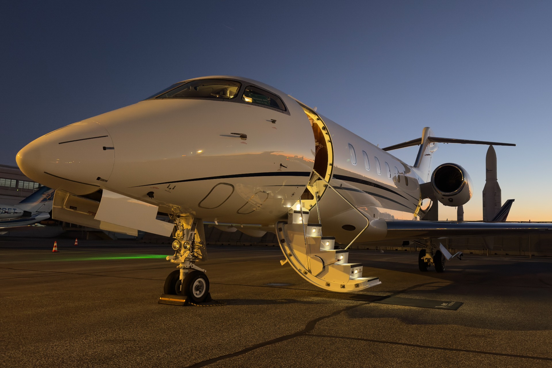 Private jet parked at night with its boarding stairs illuminated.