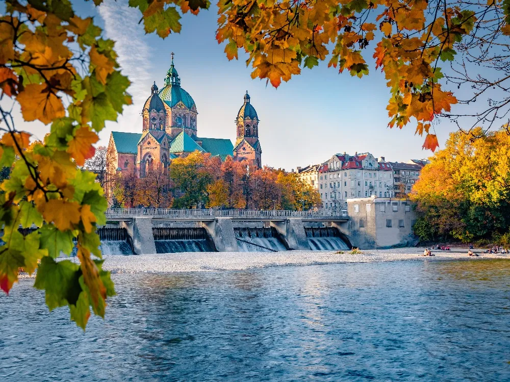 La ville de Munich durant l'automne au premier plan un barrage d'eau et au second plan une église emblématique de la ville