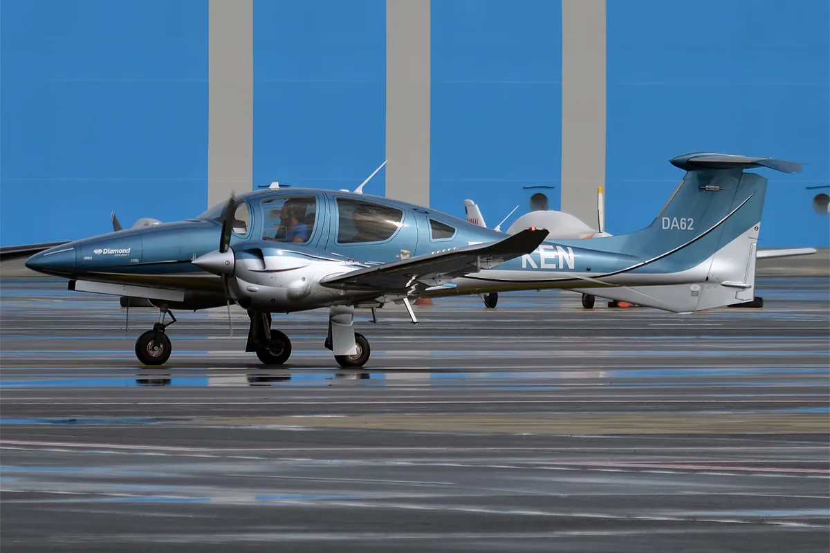 Diamond DA62 immatriculé ES-KEN au sol devant un hangar bleu